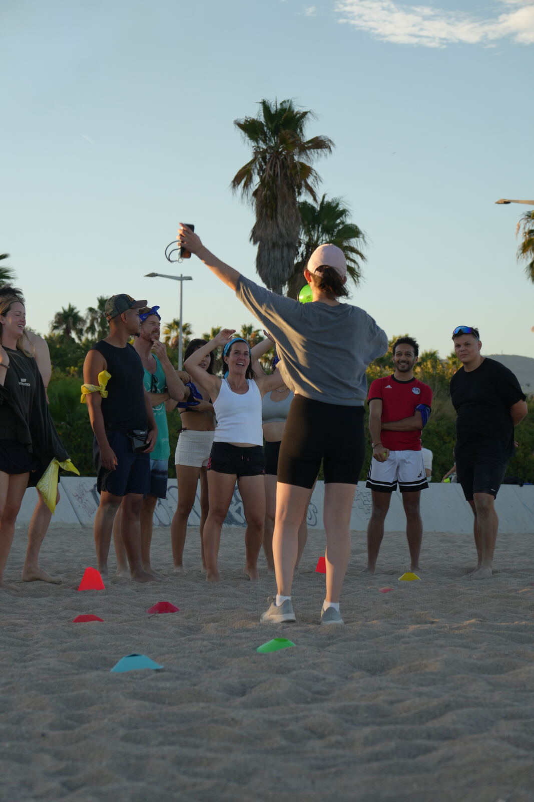 A team gathered in a circle with cones laid out on the sand