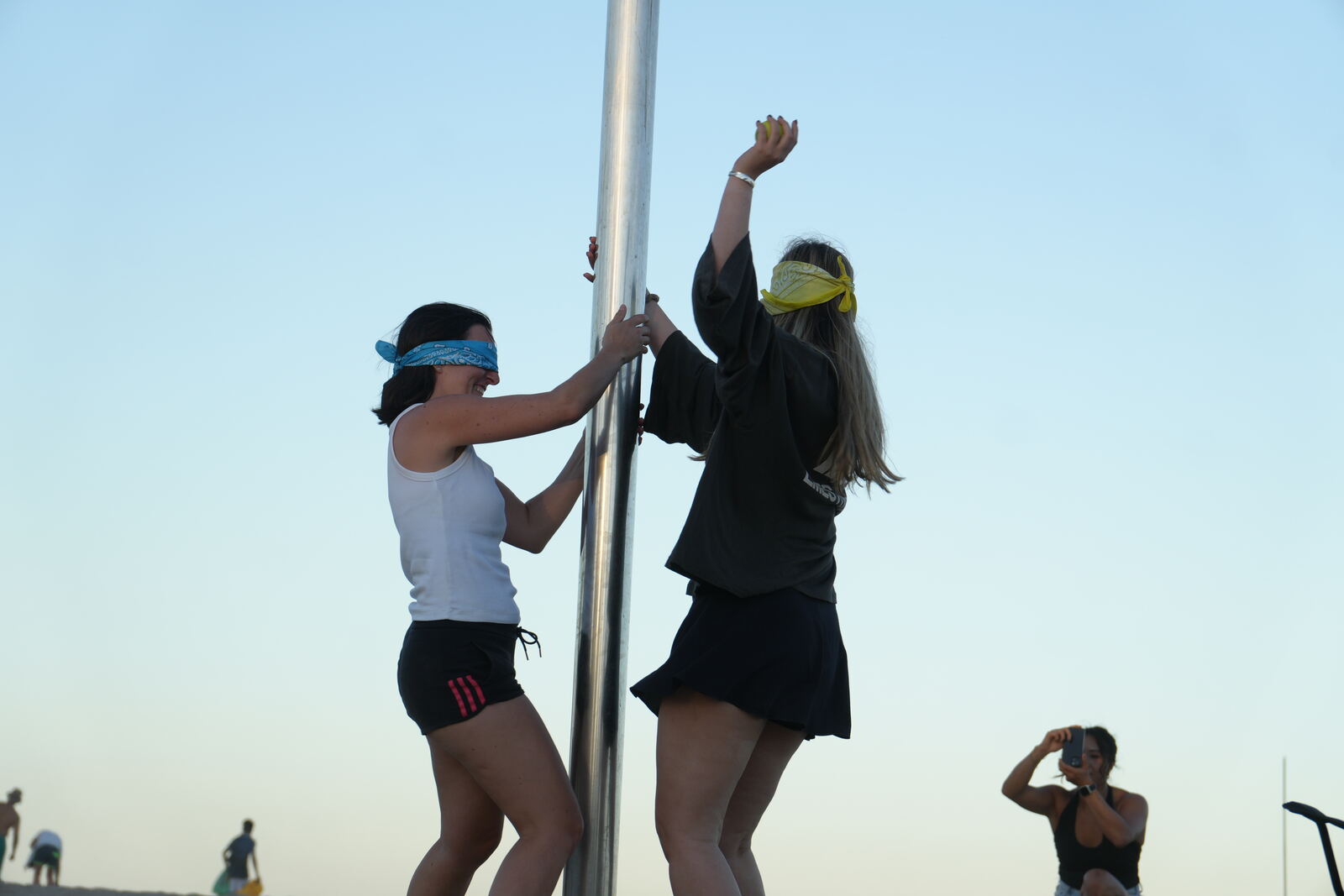 Two players blindfolded, balancing against a pole together